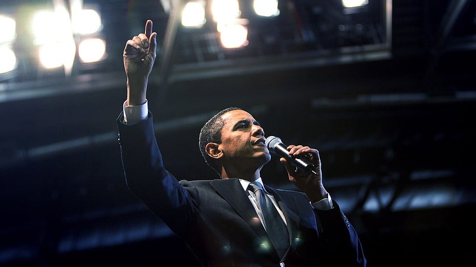 Barack Obama delivering a speech beneath stage lights